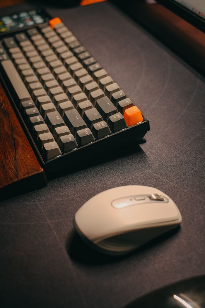 Services Close-up of a sleek computer keyboard and white mouse on a dark desk, perfect for tech enthusiasts.