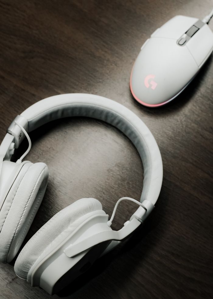Tigflow | Computer Peripherals Supplier White headphones and computer mouse on a wooden table, showcasing modern electronics.