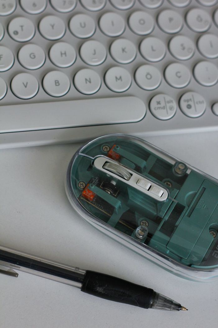 Tigflow | Computer Peripherals Supplier A top-down view of a keyboard, transparent mouse, and pen on a white desk, showcasing modern office essentials.