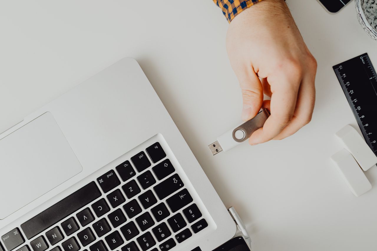 Services Hand inserting USB drive into laptop. Modern tech connection concept.